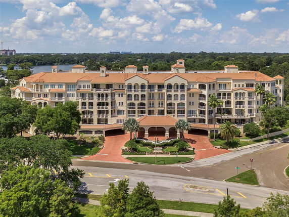 Front view of a large multi-story residential building with a red-tiled roof and balconies.