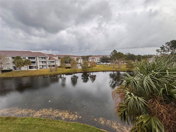 Panoramic view of apartment buildings and a lake under cloudy skies.