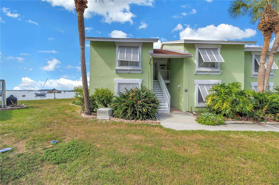 Front view of a two-story house with green exterior and stairs leading to the entrance.