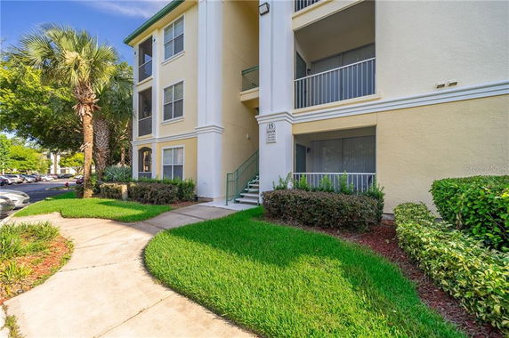 Front view of a three-story apartment building with balconies and landscaped surroundings.