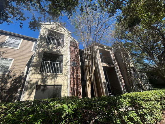 Front view of a multi-story building with balconies and a stairway entrance.