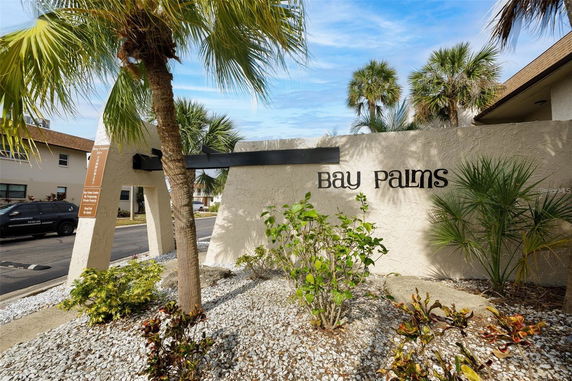 Front view of Bay Palms building entrance with palm trees and signage.