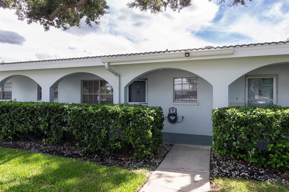 Front view of a single-story house with arches and hedges.