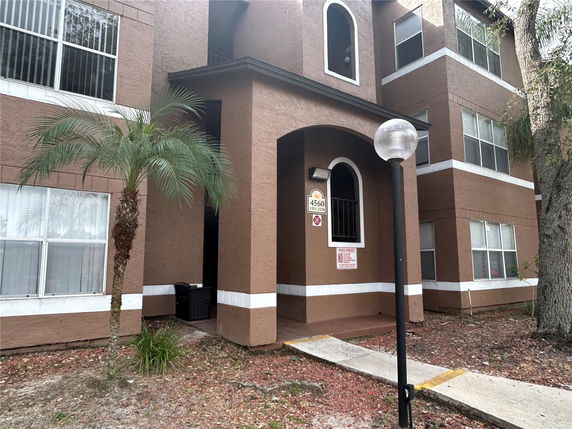 Front view of a multi-story brown building with arched entryway and multiple windows.