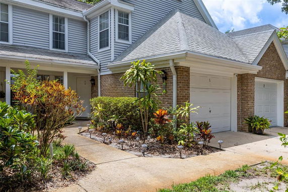 Front view of a house with a two-car garage and plants along the driveway.