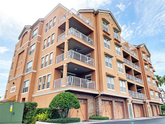 Front view of a multi-story building with balconies and garage doors.