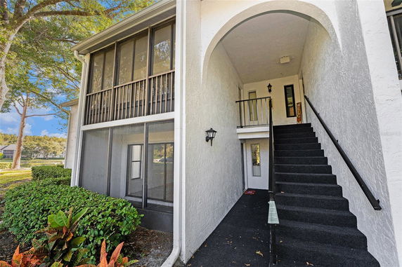Front view of a two-story building with an exterior staircase and screened balconies.