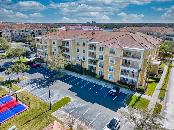 Front view of a multi-story apartment building with balconies and tiled roof.