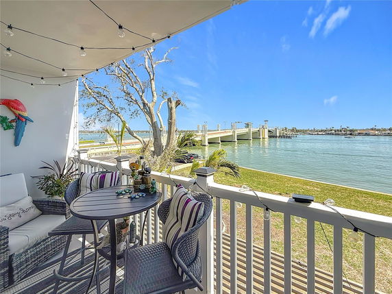 Balcony view of a river with a bridge and grassy area.