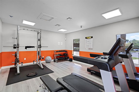 Indoor gym area with exercise equipment including treadmills and weights.