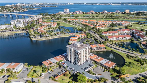 Aerial view of a coastal residential area with a significant body of water, bridges, and multiple buildings.