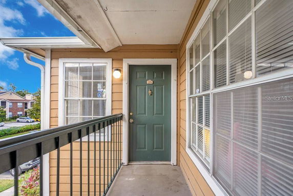 Front view of an apartment with a green door and large windows.