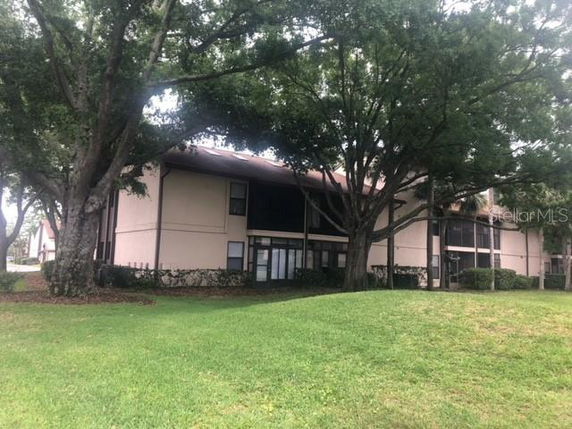 Front view of a two-story building with a sloped roof surrounded by trees and grass.