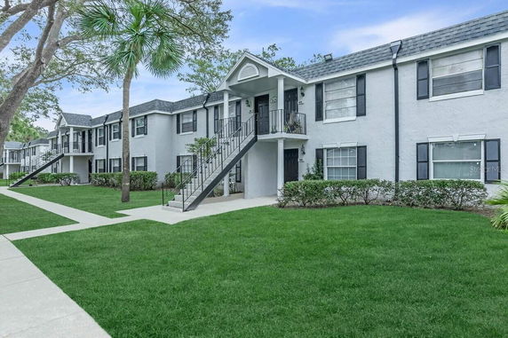 Front view of a two-story apartment building with exterior stairs and a gable roof.