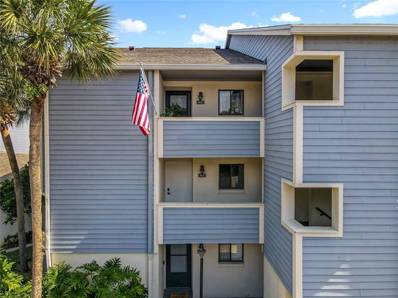 Front view of a multi-story building with balconies and an American flag.