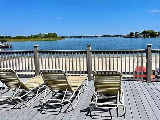 Deck area with sun loungers overlooking a lake and sandy beach.
