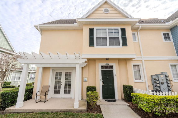 Front view of a two-story house with a light yellow facade and green door.