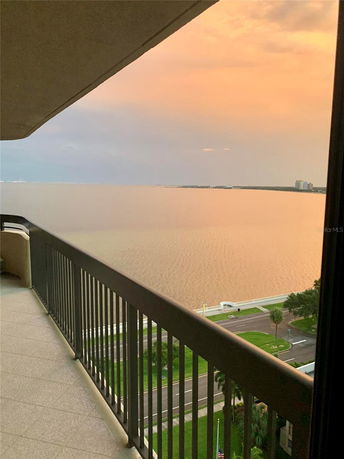 Wide angle view of a sunset over water seen from a balcony of a building.