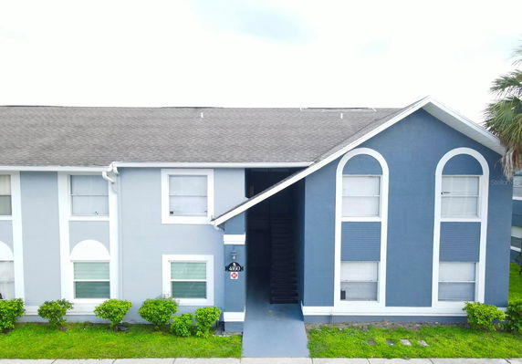 Front view of a two-story building with blue and white facade and stairway entrance.
