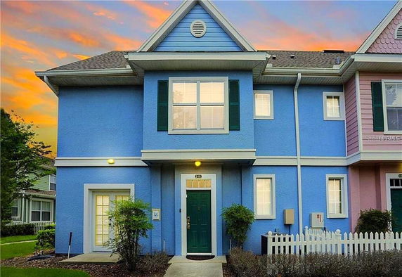 Front view of a two-story house with a blue facade and green shutters.