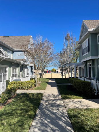 Front view of adjacent two-story houses with picket fences and a walkway in between.