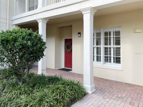 Front view of a house with a red door and multiple white-framed windows.