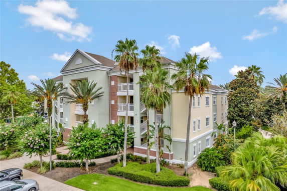 Front view of a multi-story residential building with balconies and palm trees.