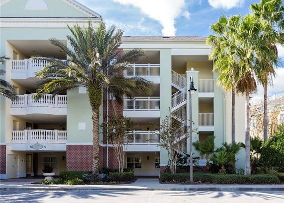 Front view of a multi-story building with balconies and palm trees.