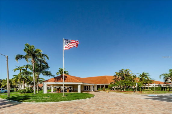 Front view of a single-story building with a red roof and an American flag in front.