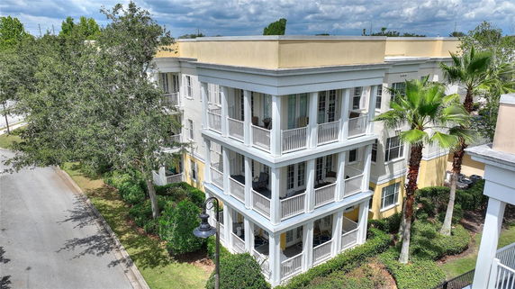 View of a three-story building with white railings and yellow walls.