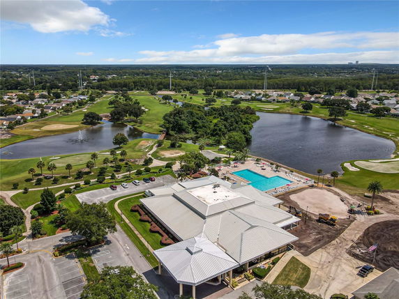 Panoramic view of a community area with a swimming pool, parking lot, and adjacent golf course.