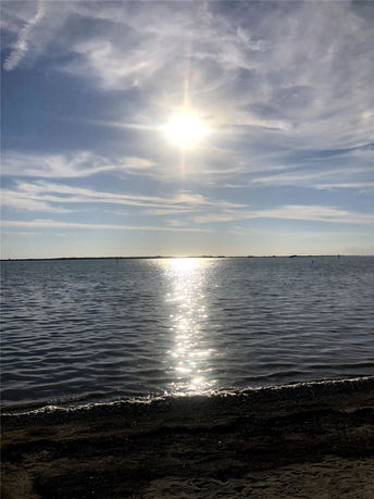 Wide angle view of a beach with the sun reflecting on the water.