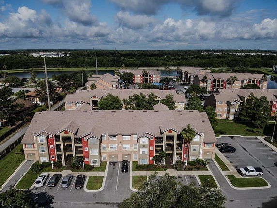 Aerial view of a residential complex with multiple apartment buildings and parking spaces.