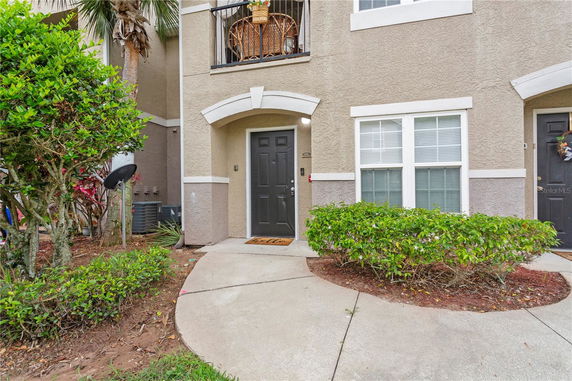 Front view of a house entrance with a dark door and small balcony above.