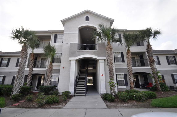Front view of a multi-story residential building with balconies and a central staircase.