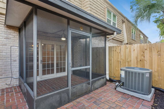 Rear view of a house featuring a screened porch and air conditioning unit.