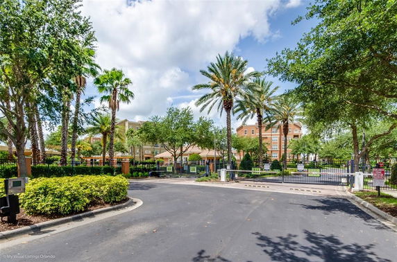 Front view of a multi-story residential building with gated entrance and palm trees.
