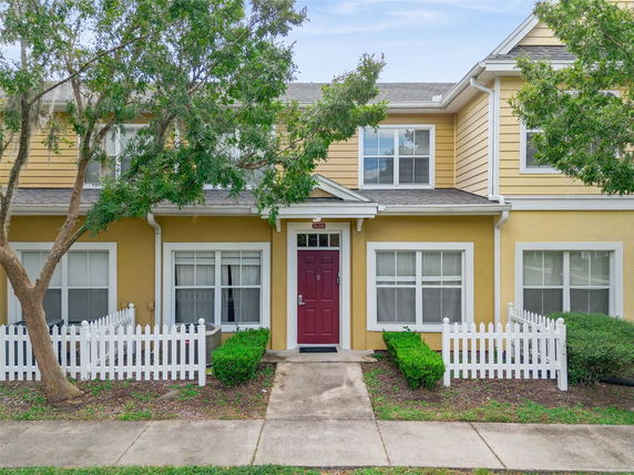 Front view of a two-story house with a red door and white picket fence.