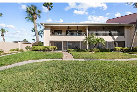 Front view of a two-story house with a balcony and a well-maintained lawn.