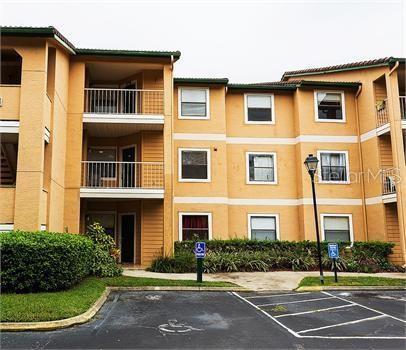 Front view of a multi-story apartment building with balconies and parking spaces.