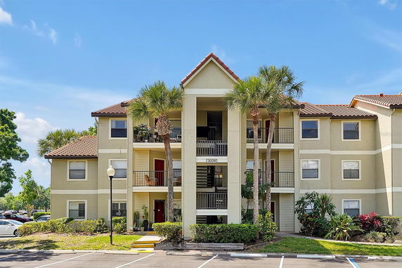 Front view of a multi-story apartment building with balconies and tiled roof.