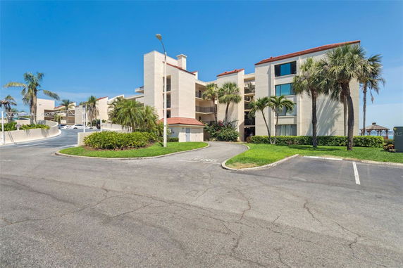 Front view of a multi-story building with balconies and palm trees.