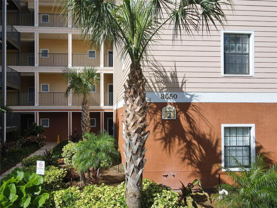 Front view of a multi-story building with balconies and palm trees.
