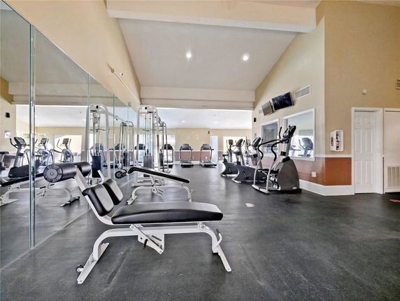 Indoor gym area with exercise equipment and mirrored walls.