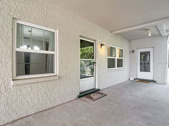 Front view of a house entrance with windows and two doors.