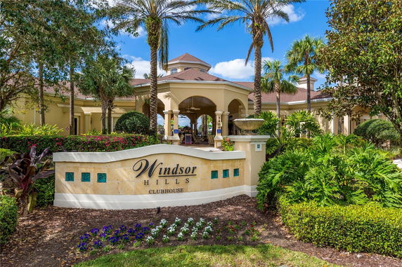 Front view of a clubhouse with a tropical garden and palm trees.