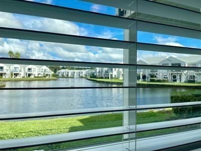 View of a lake and several buildings from behind window blinds.