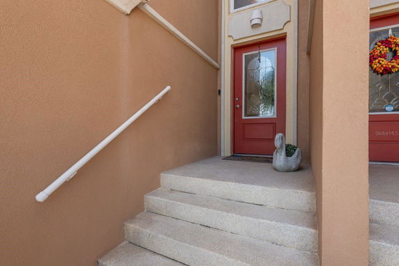 Entrance view with red door and steps leading up to it.