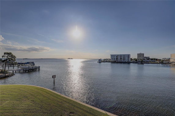 Wide view of water with buildings and docks in the distance under a clear sky.