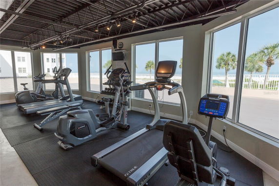 Indoor gym area with exercise equipment and large windows.